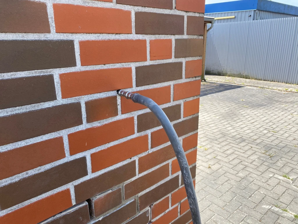 Ein Schlauch zum Dämmstoff einschäumen an einer Außenfassade